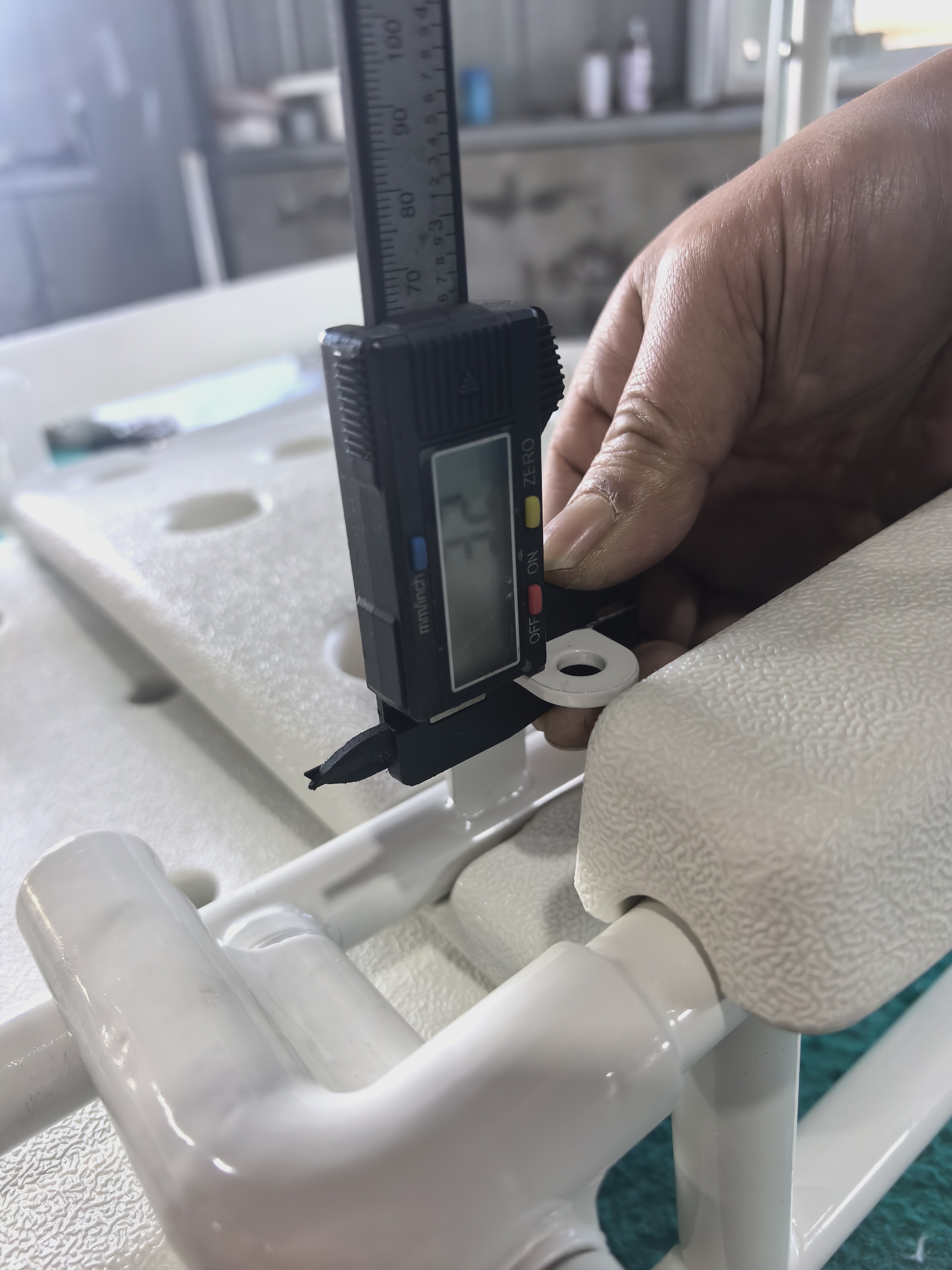 Worker checking a shower chair component with a digital measuring tool